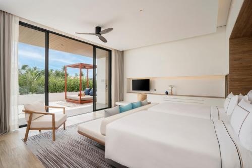 a bedroom with a large white bed and a living room at Meliá Phuket Mai Khao in Mai Khao Beach