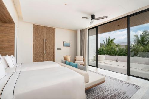 a bedroom with two beds and a large window at Meliá Phuket Mai Khao in Mai Khao Beach