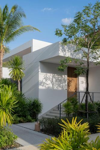 a white house with palm trees and plants at Meliá Phuket Mai Khao in Mai Khao Beach
