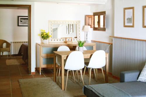 a dining room with a table and white chairs at El Celler de la Guàrdia in Montserrat