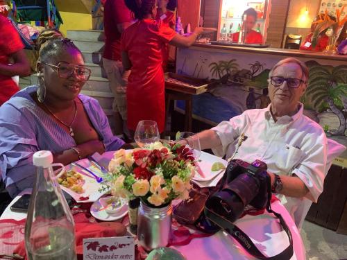 a man and woman sitting at a table with a camera at Hôtel Restaurant Coco Lodge Majunga in Mahajanga