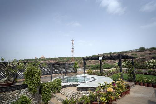 a garden with a swimming pool and a pergola at The Almond Tree in Jodhpur