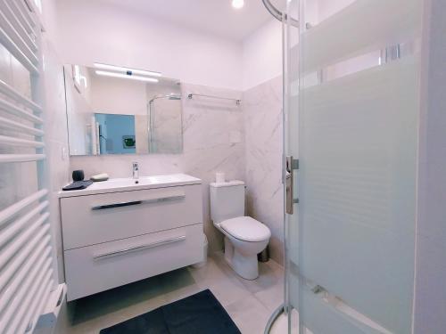 une salle de bain blanche avec des toilettes et un lavabo dans l'établissement Lalanne Btz, Duplex Jardinet près de la Plage, à Biarritz