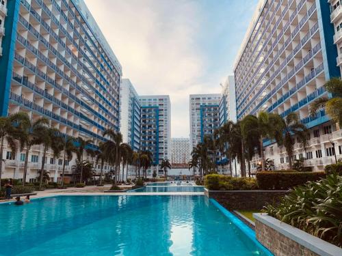 a swimming pool in the middle of two tall buildings at Sea Residences JO Alano's Place in Manila