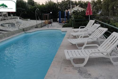 a group of white chairs next to a swimming pool at Refúgio Serrano Covilhã Serra da Estrela in Covilhã