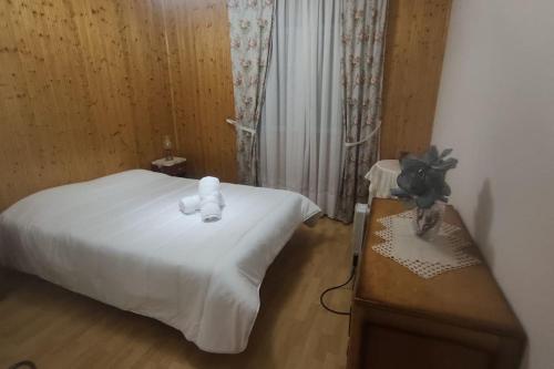Schlafzimmer mit einem weißen Bett und einem Holztisch in der Unterkunft Refúgio Serrano Covilhã Serra da Estrela in Covilhã