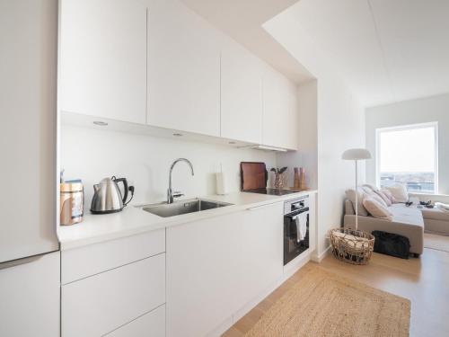 a white kitchen with a sink and a couch at New Danish Design flat - 10 minutes to city centre in Copenhagen
