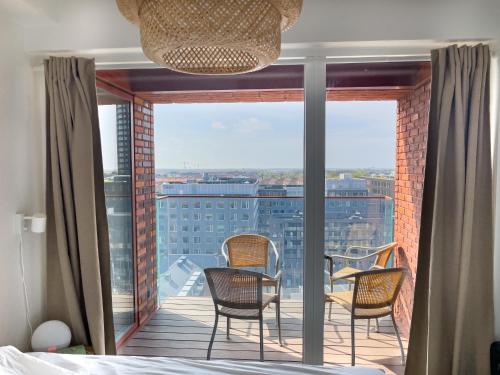 a bedroom with a bed and chairs on a balcony at New Danish Design flat - 10 minutes to city centre in Copenhagen