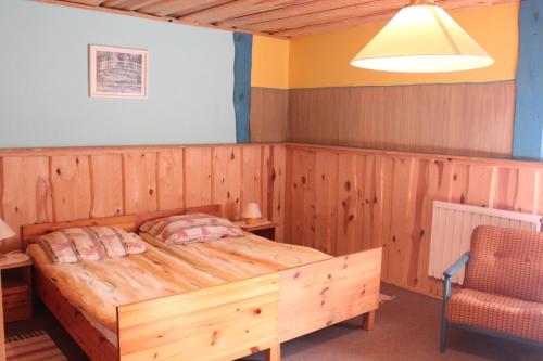 a bedroom with a wooden bed and a chair at Agroturystyka Kociewiak in Szteklin