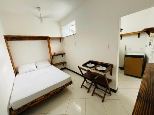 a small bedroom with a bed and a table at Kitnet encantadora, equipada, conforto no centro in Caratinga