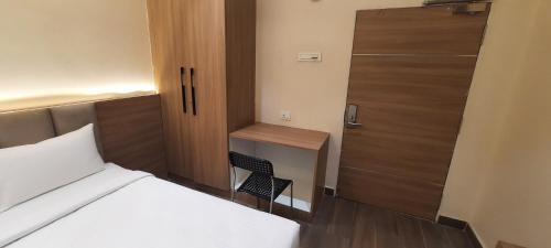 a bedroom with a bed and a desk with a chair at HOTEL SUNRISE HOSPITALITY in Vijayawāda