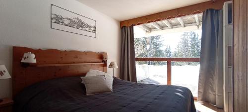 a bedroom with a bed and a large window at Bel appart pour 4/6 pers plein SUD sans vis a vis in Chamrousse
