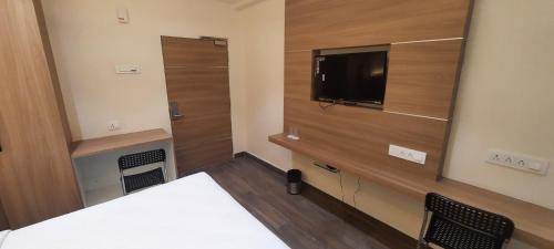 a bedroom with a bed and a tv and a mirror at HOTEL SUNRISE HOSPITALITY in Vijayawāda