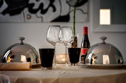 three wine glasses sitting on a table with wine bottles at LHP Hotel Montecatini Palace & SPA in Montecatini Terme
