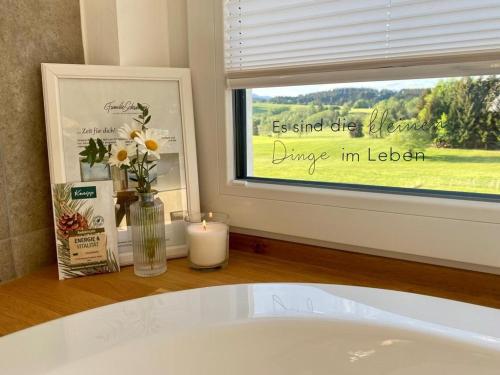 a bathroom with a window with a vase of flowers and a candle at ALPEN WOHLFÜHLQUARTIER in Bayersoien