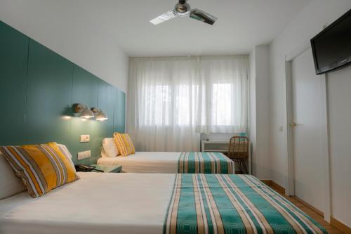 a hotel room with two beds and a television at Yomo Hostal BCN Port in Barcelona