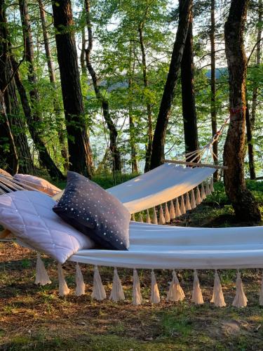 a hammock in the woods with two pillows on it at Caravana Juliana - Glamping in Swaderki
