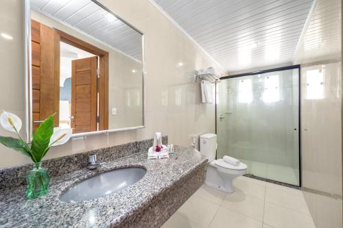 a bathroom with a sink and a toilet and a mirror at Hotel Porto Napolis in Eunápolis