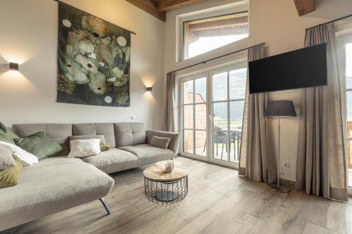 a living room with a couch and a large window at Tauernlodges Uttendorf by ALPS RESORTS in Uttendorf