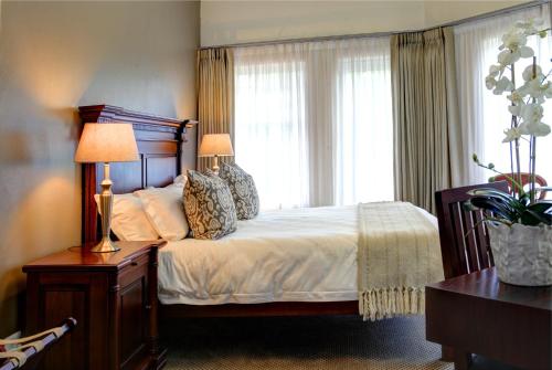 a bedroom with a bed with two lamps and a window at Cinnamon Boutique Guest House in Wilderness
