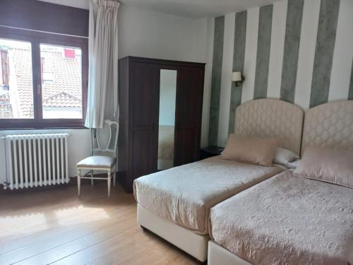 a bedroom with a bed and a chair and a window at Marina in Ribadesella