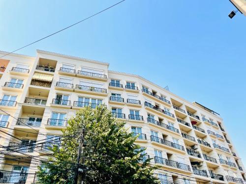 un grand bâtiment avec balcon et un arbre en face de celui-ci dans l'établissement 4 llullat - City Center Apartment, à Pristina