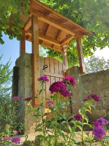 a wooden pergola on a stone wall with purple flowers at Rest House Ripac in Praščijak