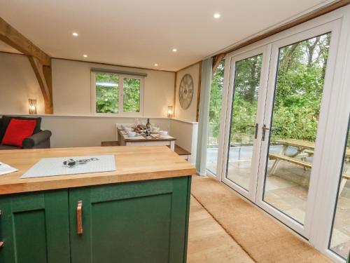 uma cozinha com armários verdes e portas de vidro deslizantes em Roman Lodge em Weymouth