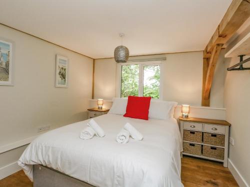 um quarto com uma cama branca e uma almofada vermelha em Roman Lodge em Weymouth