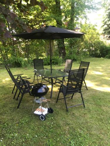 a grill and a table with chairs and an umbrella at Dwunastka in Zakopane