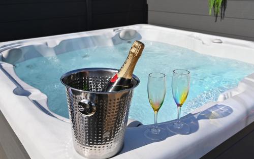 a bucket of champagne in a tub with two wine glasses at Pod 1, Sinclair bay lodges in Keiss