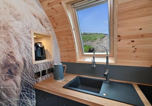 una cocina con fregadero y una ventana en una cabaña en Pod 1, Sinclair bay lodges en Keiss