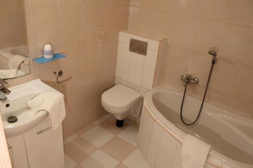 a bathroom with a toilet and a tub and a sink at Penzión Hellene in Piešťany