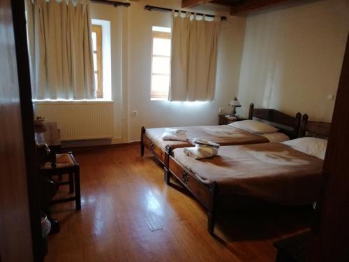 a bedroom with two beds and two windows at Abeliona Guesthouse in Ambeliona