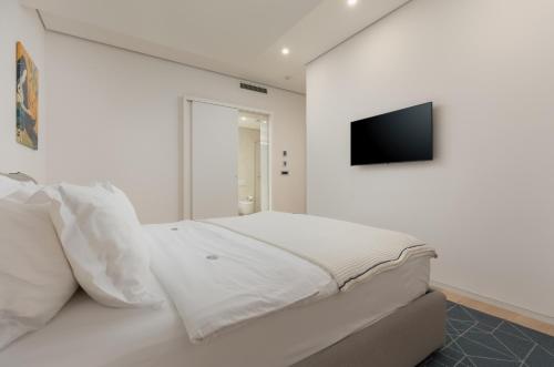 a white bedroom with a bed and a flat screen tv at Dukley Hotel & Resort in Budva