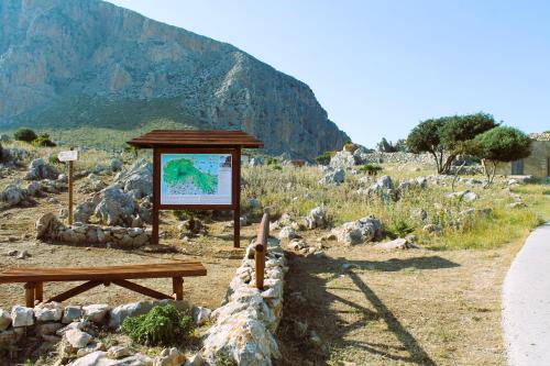 un cartel y un banco en un campo con una montaña en Ai piedi di Cofano en Custonaci
