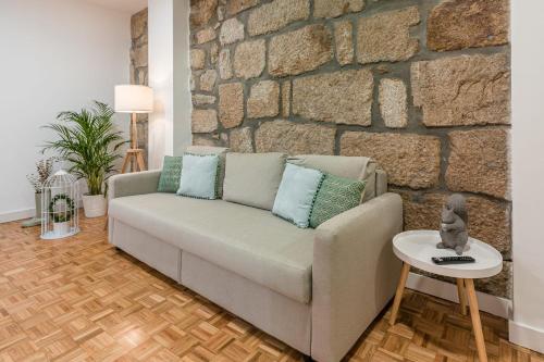 a living room with a couch and a stone wall at GuestReady - Grandeur River Terrace in Porto