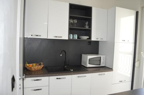 kuchnia z białymi szafkami i kuchenką mikrofalową w obiekcie Cozy Apartment Split w Splicie