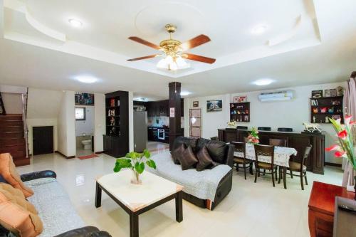 a living room with a ceiling fan and a dining room at Captivating 3-Bed Villa in Muang Pattaya in Nong Prue