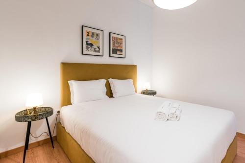 una camera con un grande letto bianco e due lampade di GuestReady - Yazdah Flat 1 a Porto