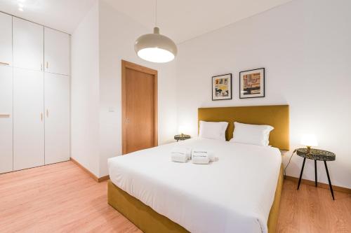 una camera da letto con un grande letto bianco con due bicchieri sopra di GuestReady - Yazdah Flat 1 a Porto