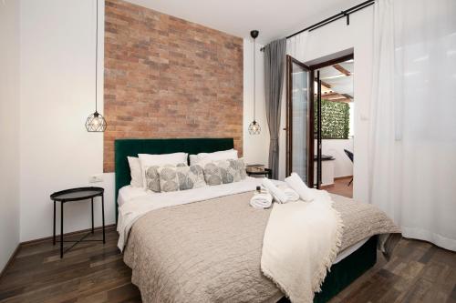 een slaapkamer met een groot bed met een bakstenen muur bij Apartments Ingrid in Pula