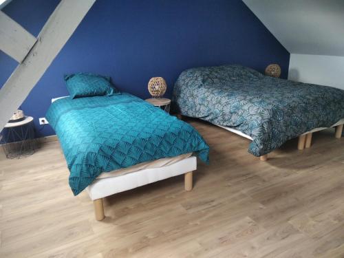 - 2 lits dans une chambre dotée de murs bleus et de parquet dans l'établissement Agréable Maison proche Etretat, à Criquetot-lʼEsneval