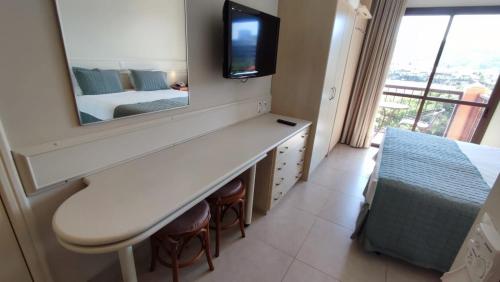 1 dormitorio con espejo, 1 cama y TV en Jurerê Beach Village, en Florianópolis