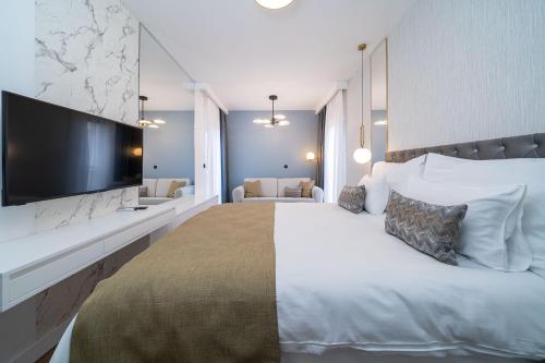 a bedroom with a large bed with a large tv on the wall at Hotel Millennium by Aycon in Budva
