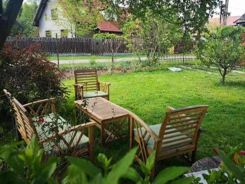three chairs and a wooden table in a yard at Red Bed in Jankowice