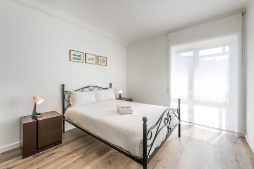 a white bedroom with a bed and a window at GuestReady - Breathtaking view at Matosinhos in Matosinhos