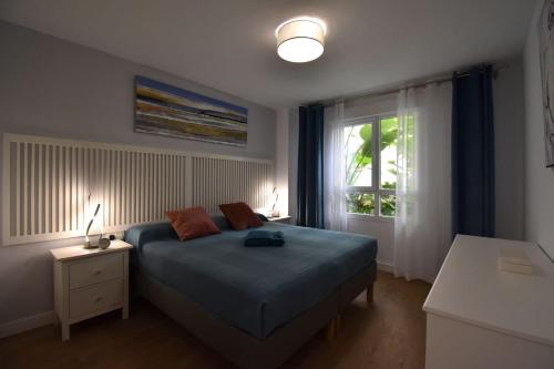 sypialnia z niebieskim łóżkiem i oknem w obiekcie MAGNOLIO APARTMENT CALACEITE w mieście Torrox Costa