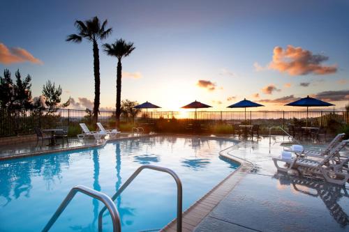une grande piscine avec des chaises et des parasols dans l'établissement Ayres Hotel & Spa Mission Viejo - Lake Forest, à Mission Viejo