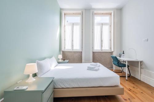 een slaapkamer met een bed, een bureau en 2 ramen bij GuestReady - Porto Home 6 in Porto
